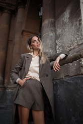 a lady in a beige top, a pair of grey shorts and a grey unisex coat